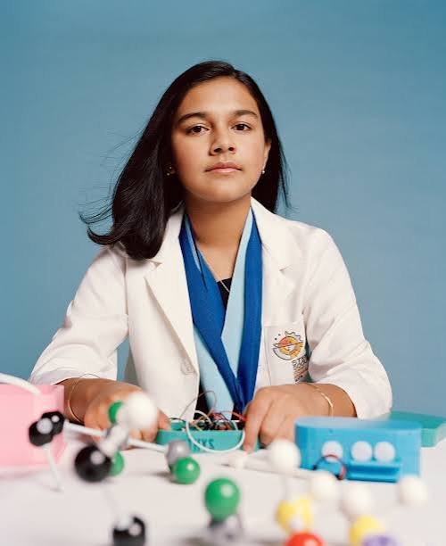 Gitanjali Rao in a lab coat at a table with molecule models